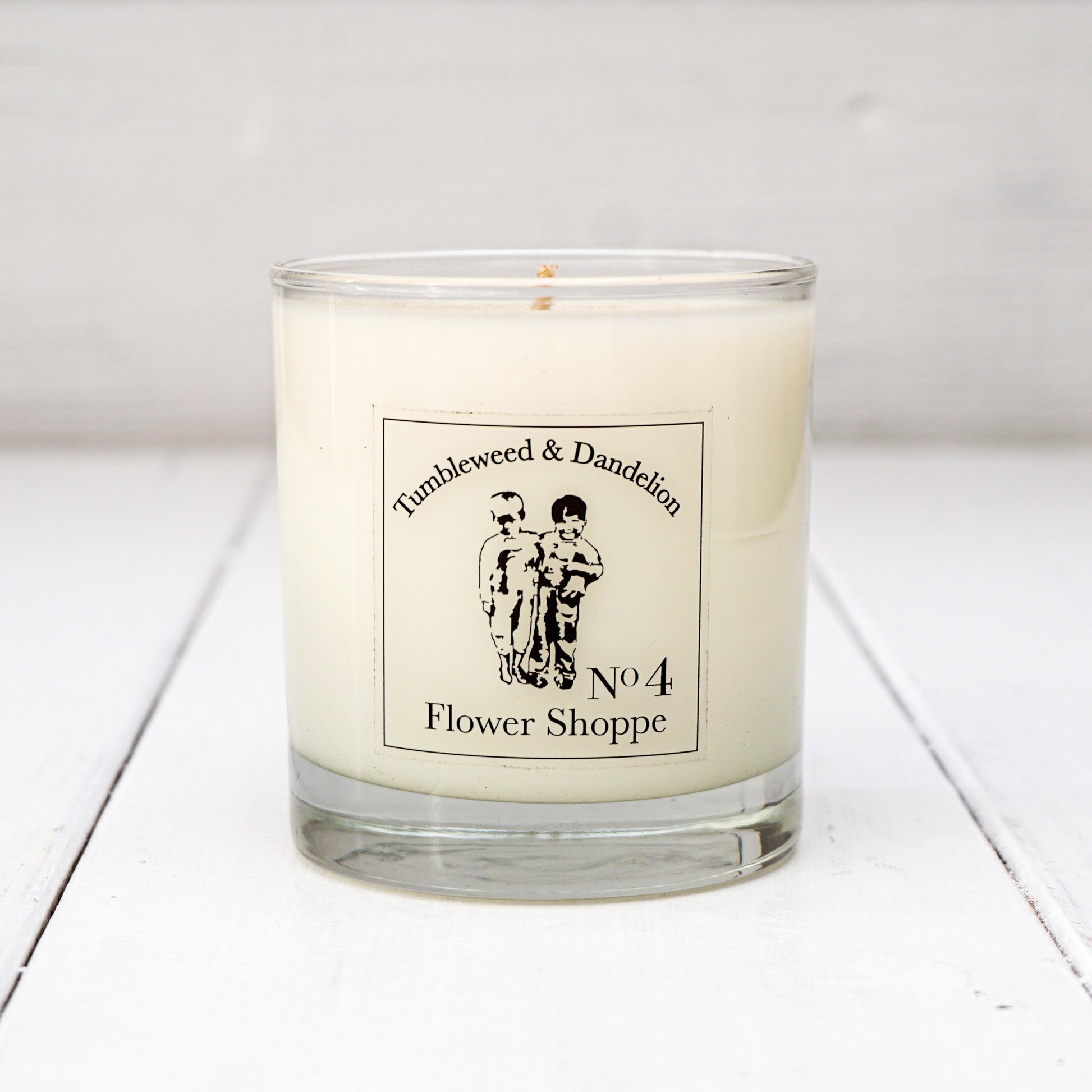 Clear glass candle with Tumbleweed and Dandelion logo, flowery scent