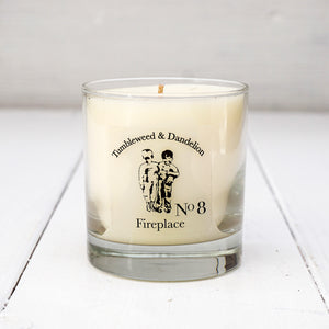 Clear glass candle with Tumbleweed and Dandelion logo, earthy fireplace scent