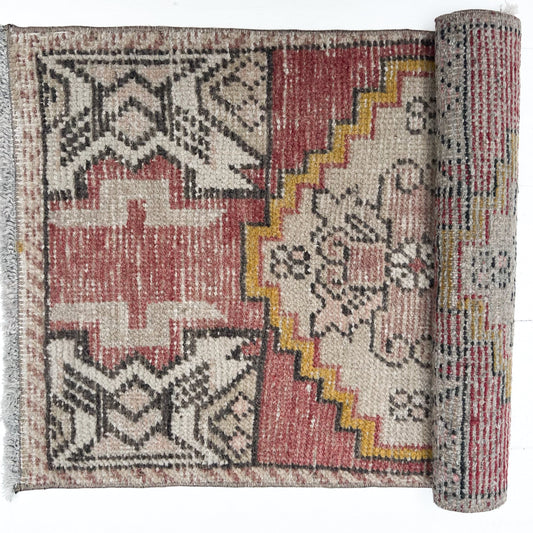 brick red, cream, gold, tan and black colored small Turkish rug