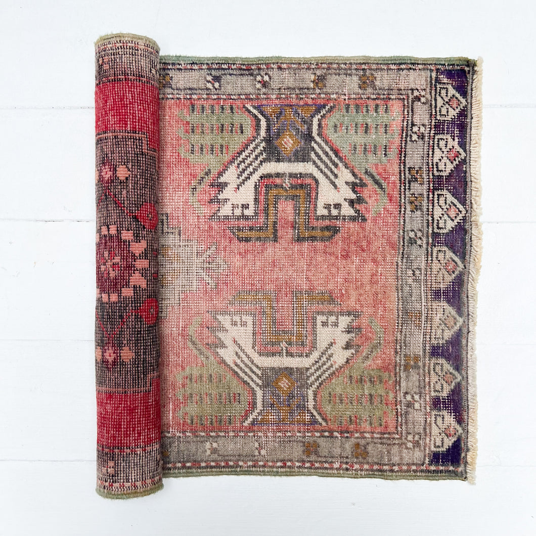 faded red, sage green, brown, tan and cream colored small Turkish rug