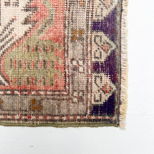 faded red, sage green, brown, tan and cream colored small Turkish rug