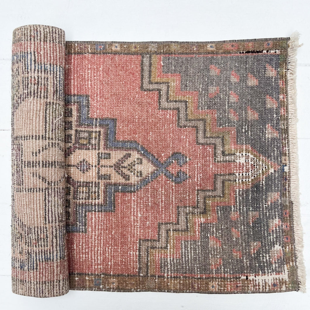 red, charcoal tan and cream colored small Turkish rug