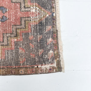 red, charcoal tan and cream colored small Turkish rug