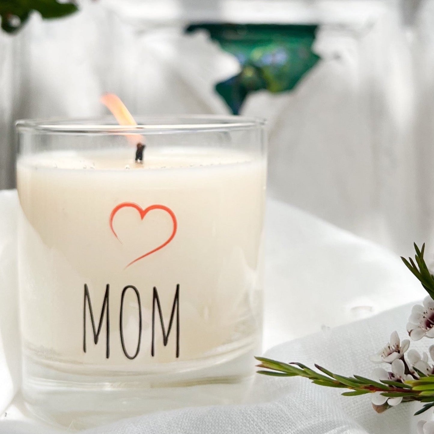 clear glass candle with MOM in black and a red heart