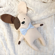 Load image into Gallery viewer, cream colored dog stuffed animal with one brown ear and light blue bowtie