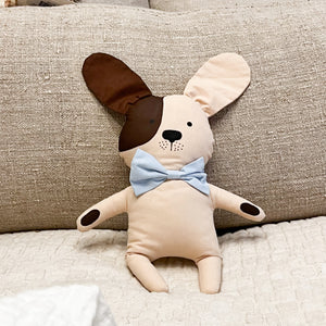 cream colored dog stuffed animal with one brown ear and light blue bowtie