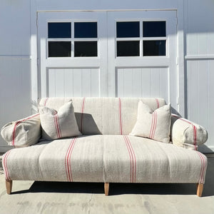 grain sack fabric sofa, natural color with thin red stripes, arm covers, two matching throw pillows and light wood legs