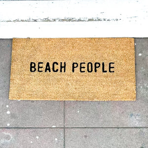brown door mat that says "beach people" in black letters
