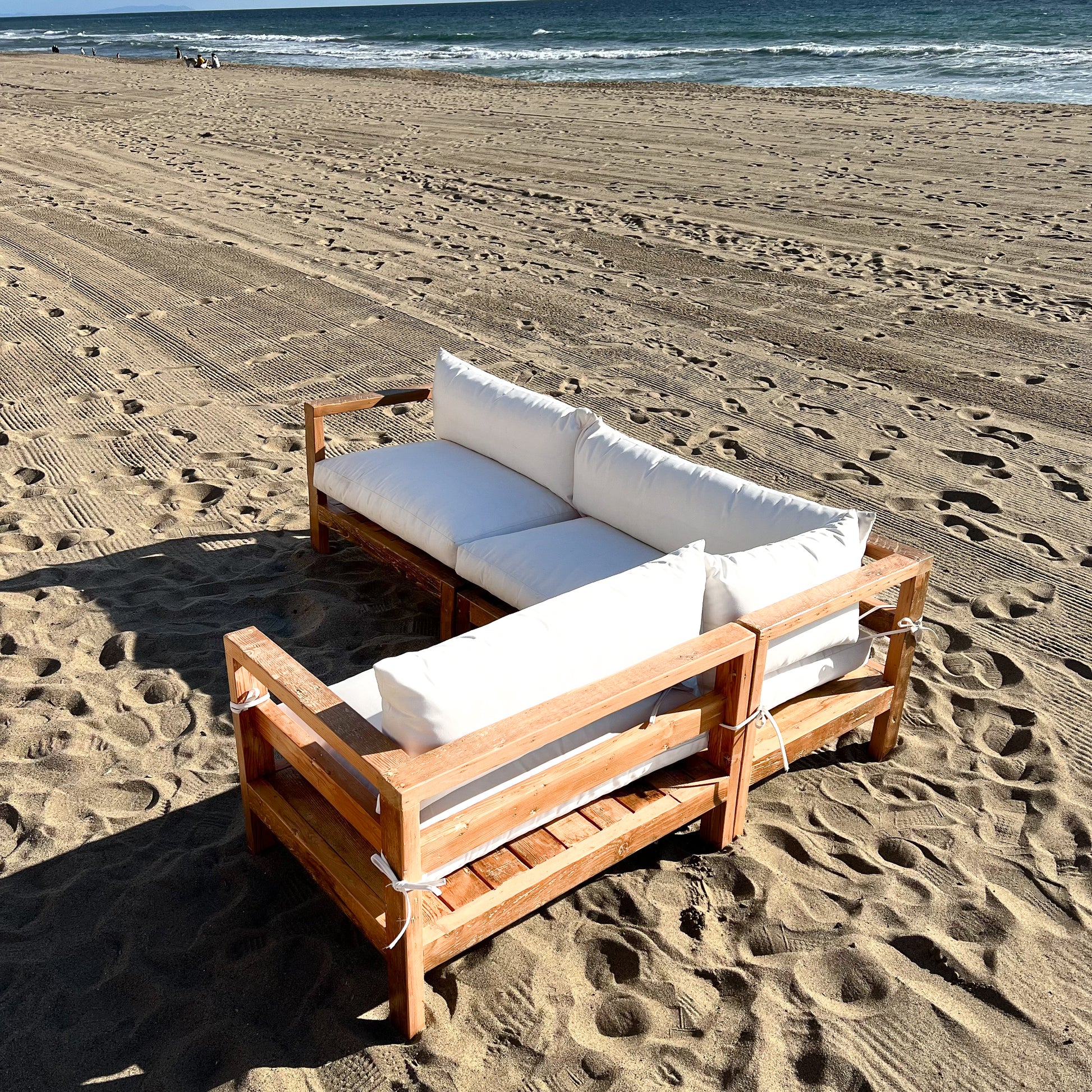 sectional sofa made of repurposed wood, off white cushions with outdoor fabric, medium brown wood color