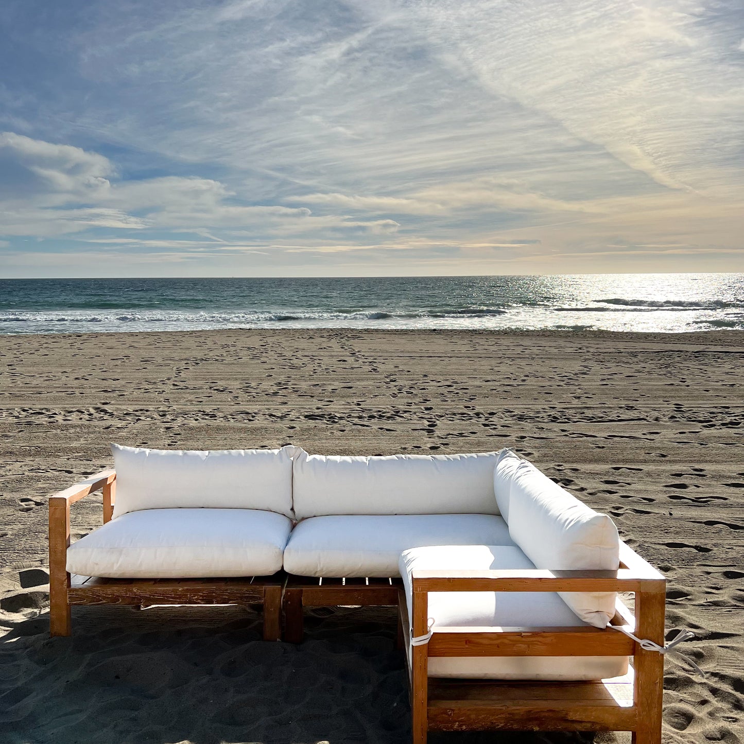 sectional sofa made of repurposed wood, off white cushions with outdoor fabric, medium brown wood color