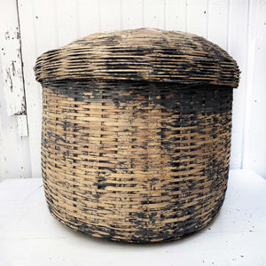 large charcoal colored wicker basket with some color worn off in middle, with lid