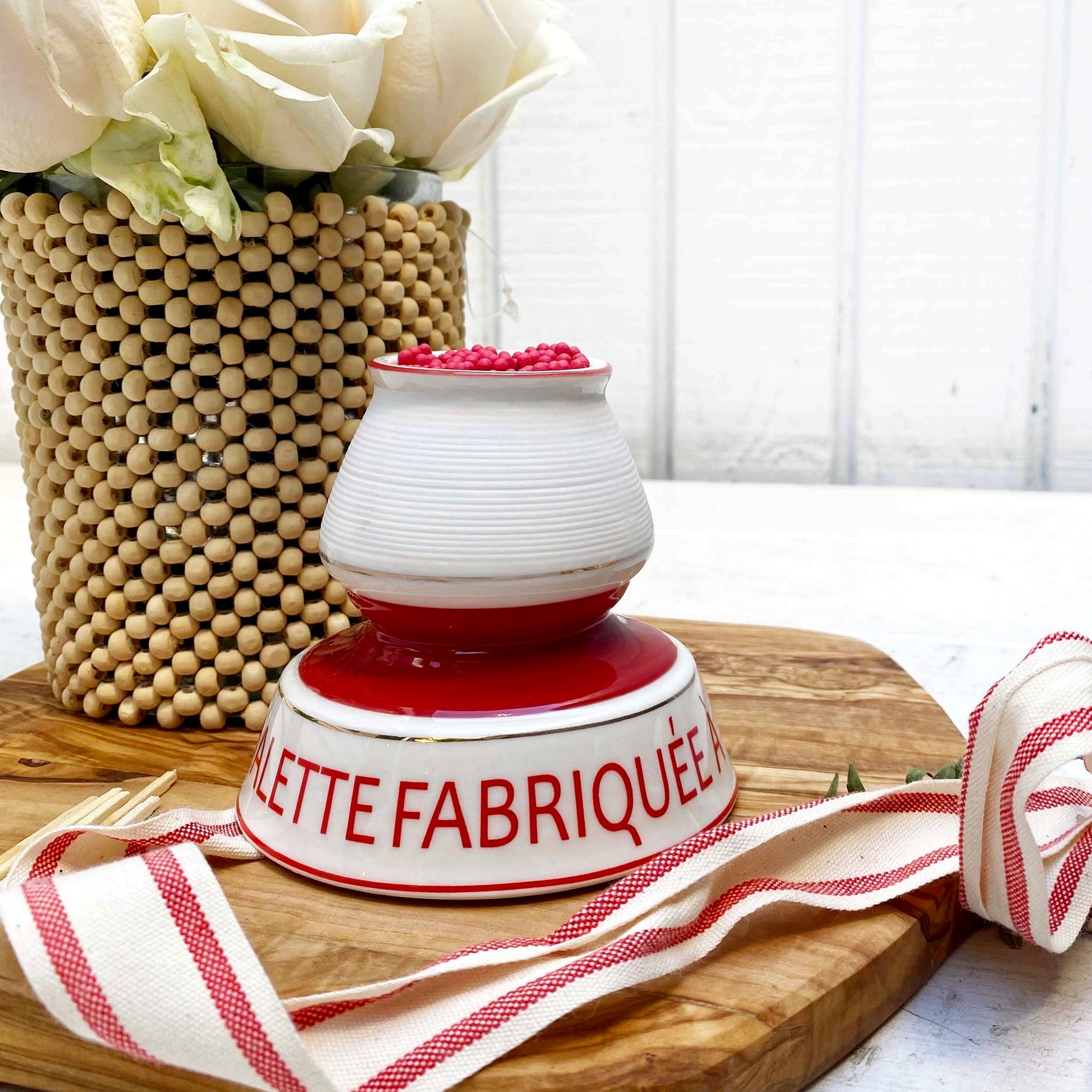 white and red ceramic match strike holder with red French lettering