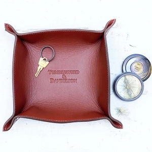 brown leather catch all tray with "tumbleweed and dandelion" embossed in the middle