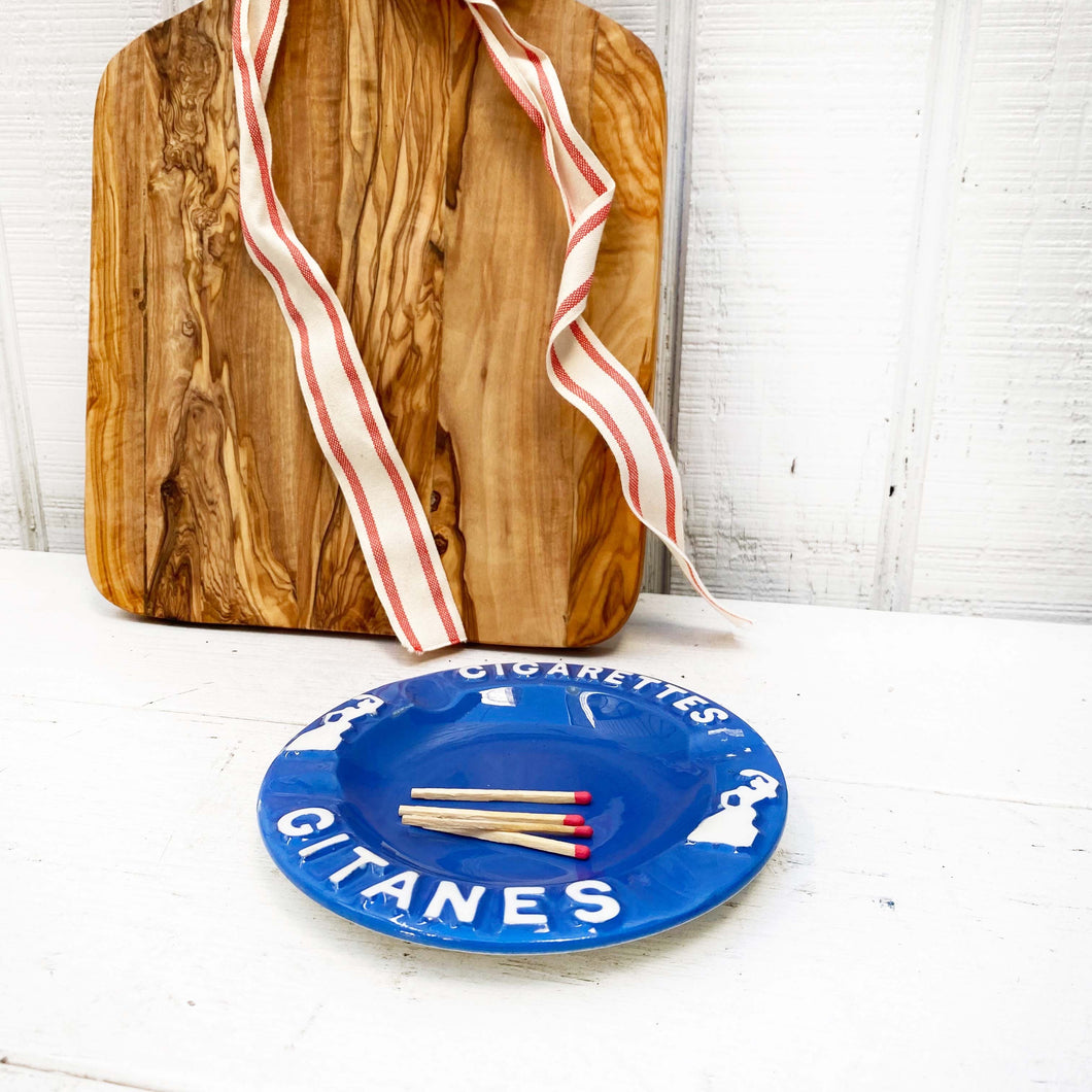 blue ashtray with French words in white on the edge
