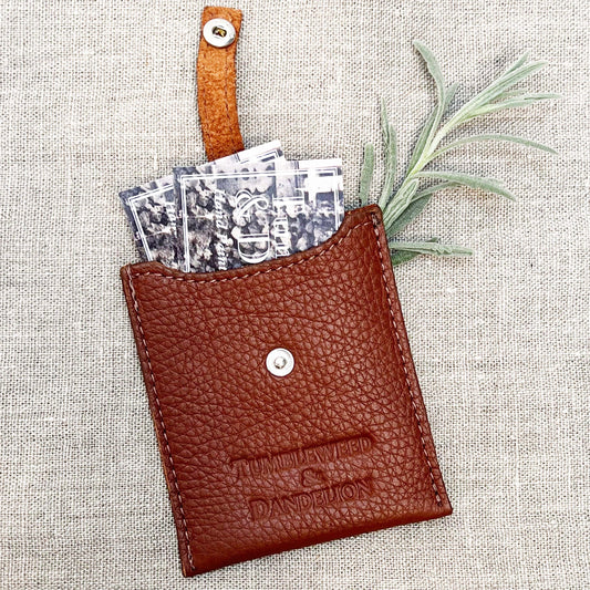 leather card holder with snap strap and "Tumbleweed & Dandelion" embossed
