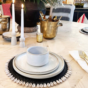 black rattan round placemat with off white shell on edge