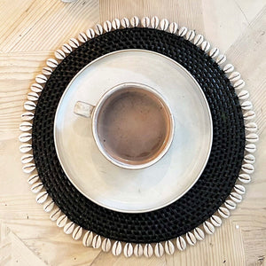black rattan placemat with off white shells on edge
