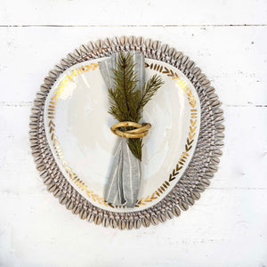 white washed rattan round placemat with off white shells on edges