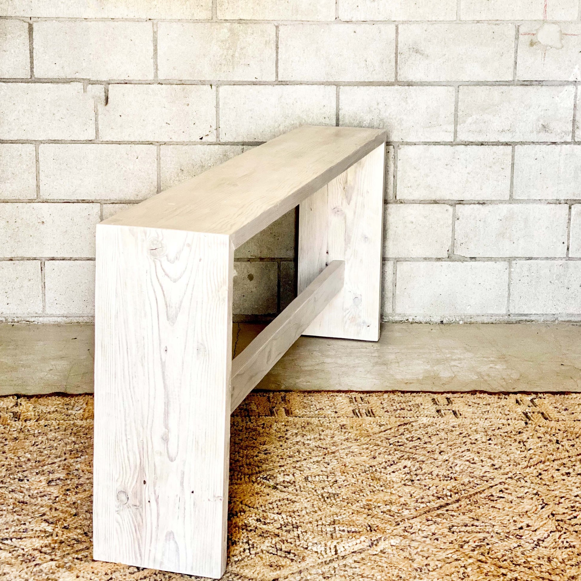 clean line bleached wooden entryway table with bar along bottom