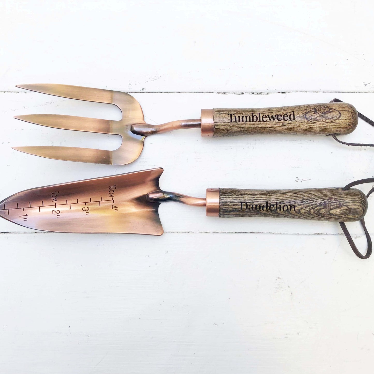 copper fork and trowel garden tool set with wooden handles imprinted with "Tumbleweed" on fork and "Dandelion" on the trowel