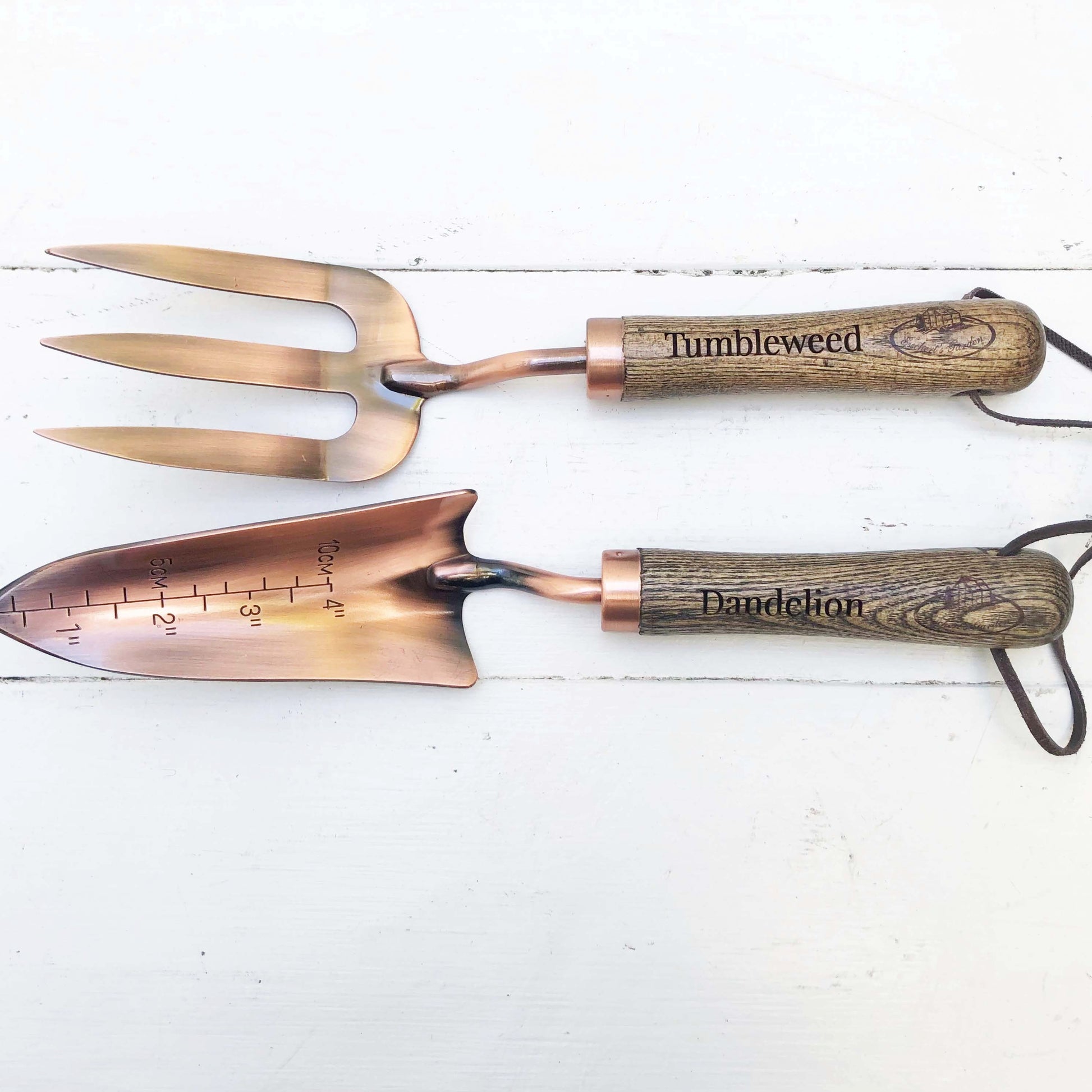 copper fork and trowel garden tool set with wooden handles imprinted with "Tumbleweed" on fork and "Dandelion" on the trowel