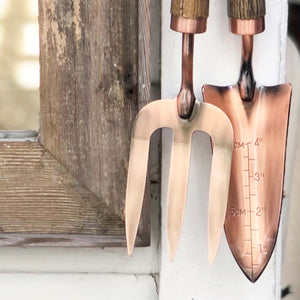 copper fork and trowel garden tool set with wooden handles imprinted with "Tumbleweed" on fork and "Dandelion" on the trowel
