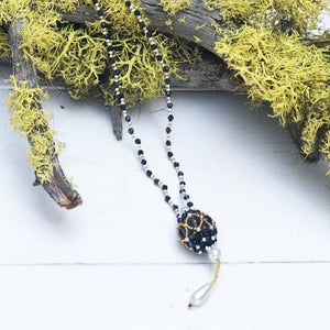 black, white and gold beaded necklace with ball pendant