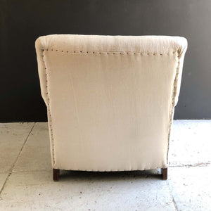 cream colored upholstered lounge chair with brown wooden feet