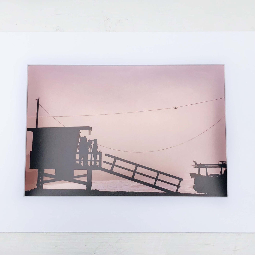 photo of a beach lifeguard station with sky tinted pink