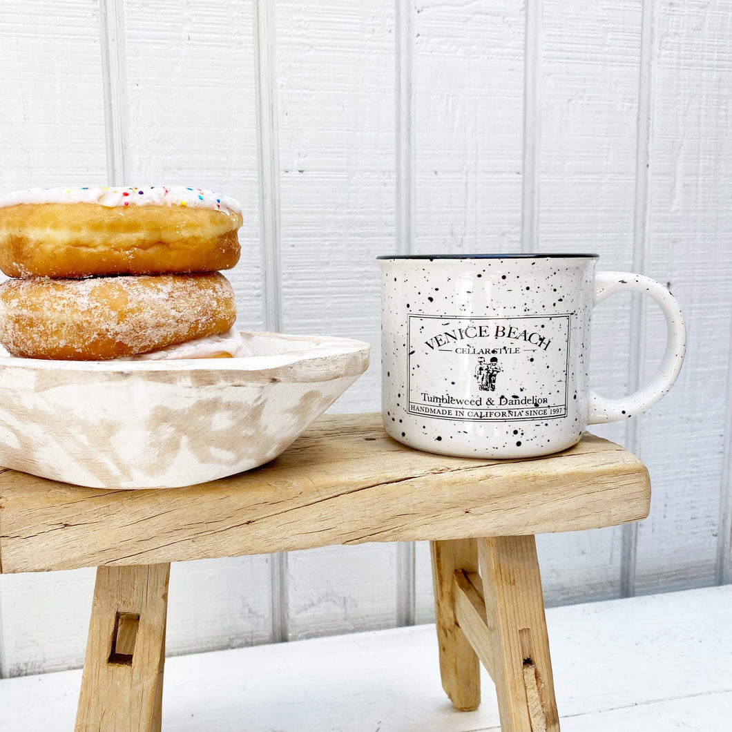 white enamel mug with black speckles and black Tumbleweed and Dandelion logo on front