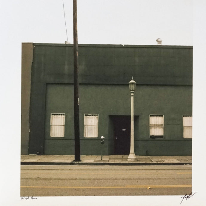 photograph of dark green building with streetlamp and telephone pole