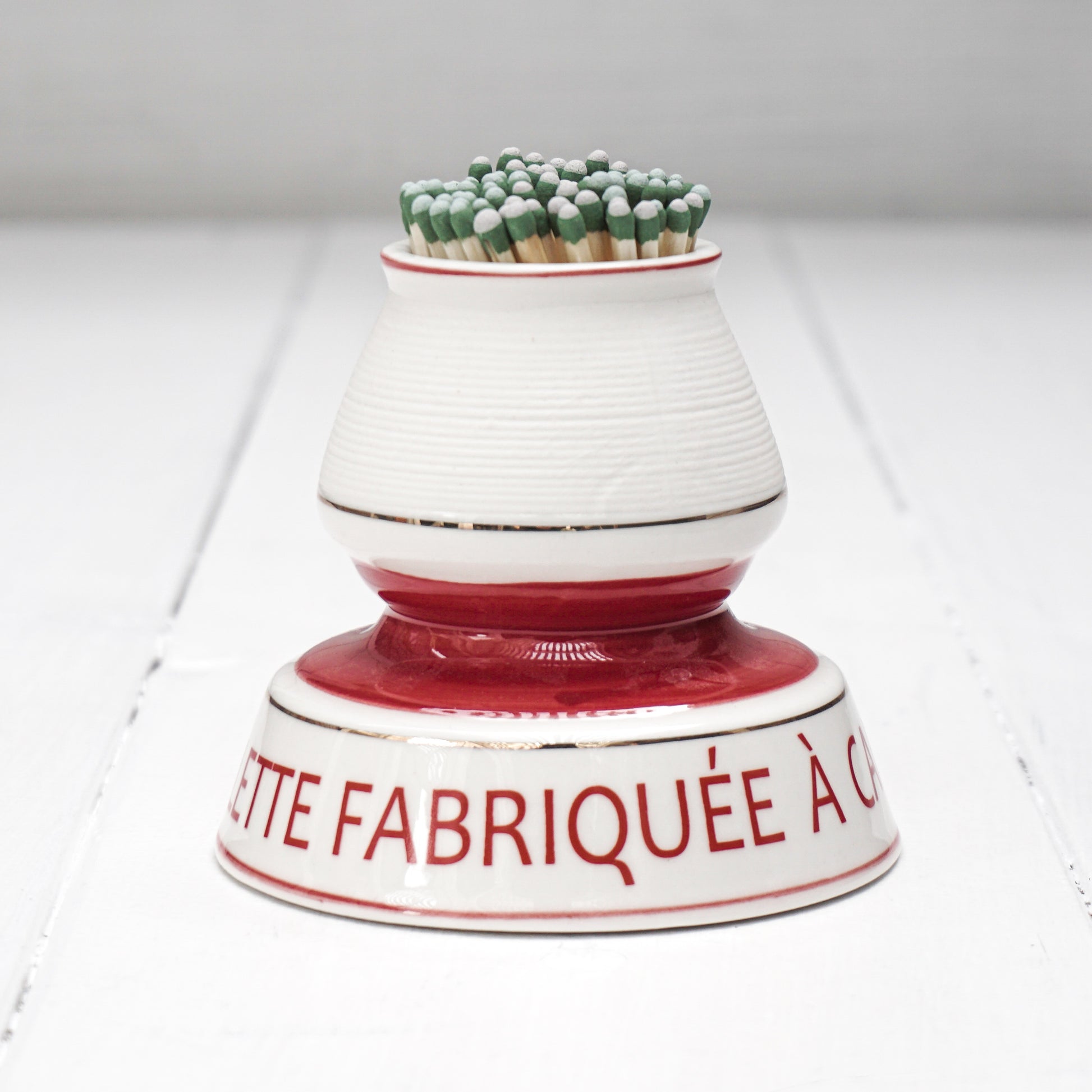 white and red ceramic match strike holder with red French lettering