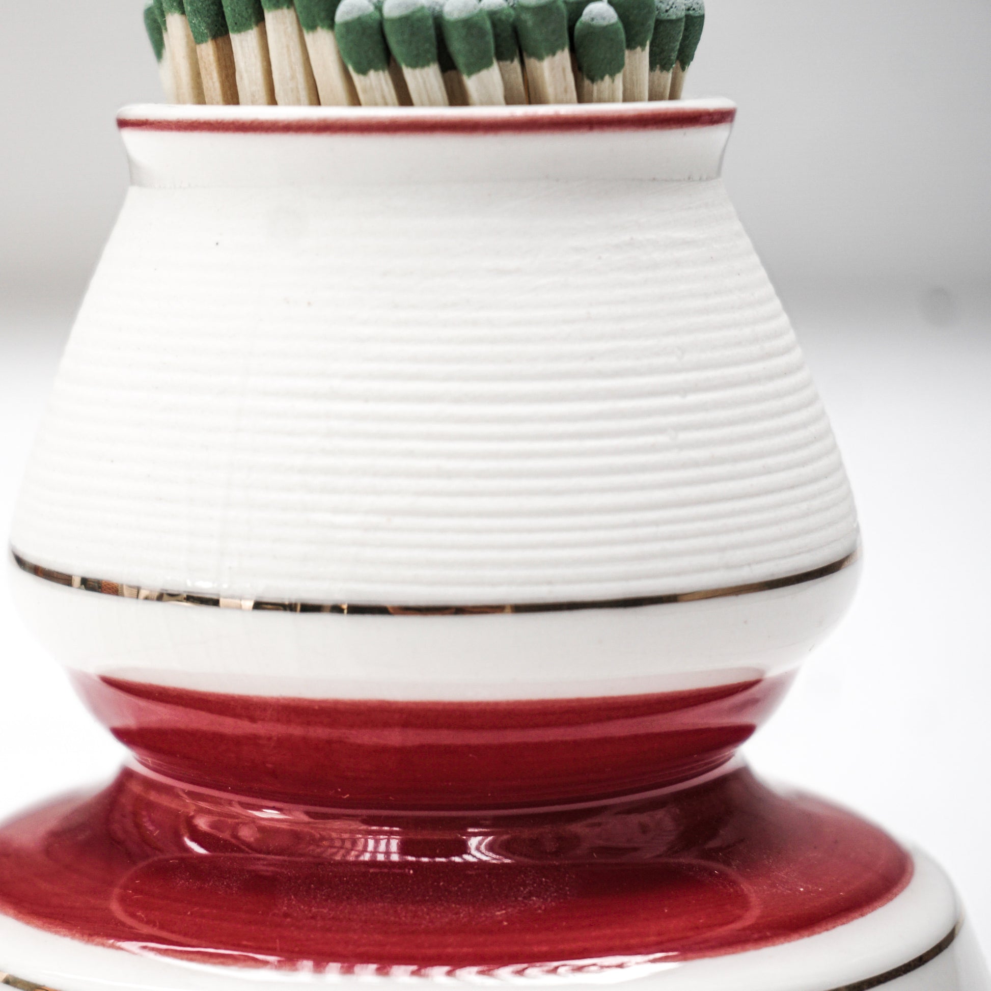 white and red ceramic match strike holder with red French lettering