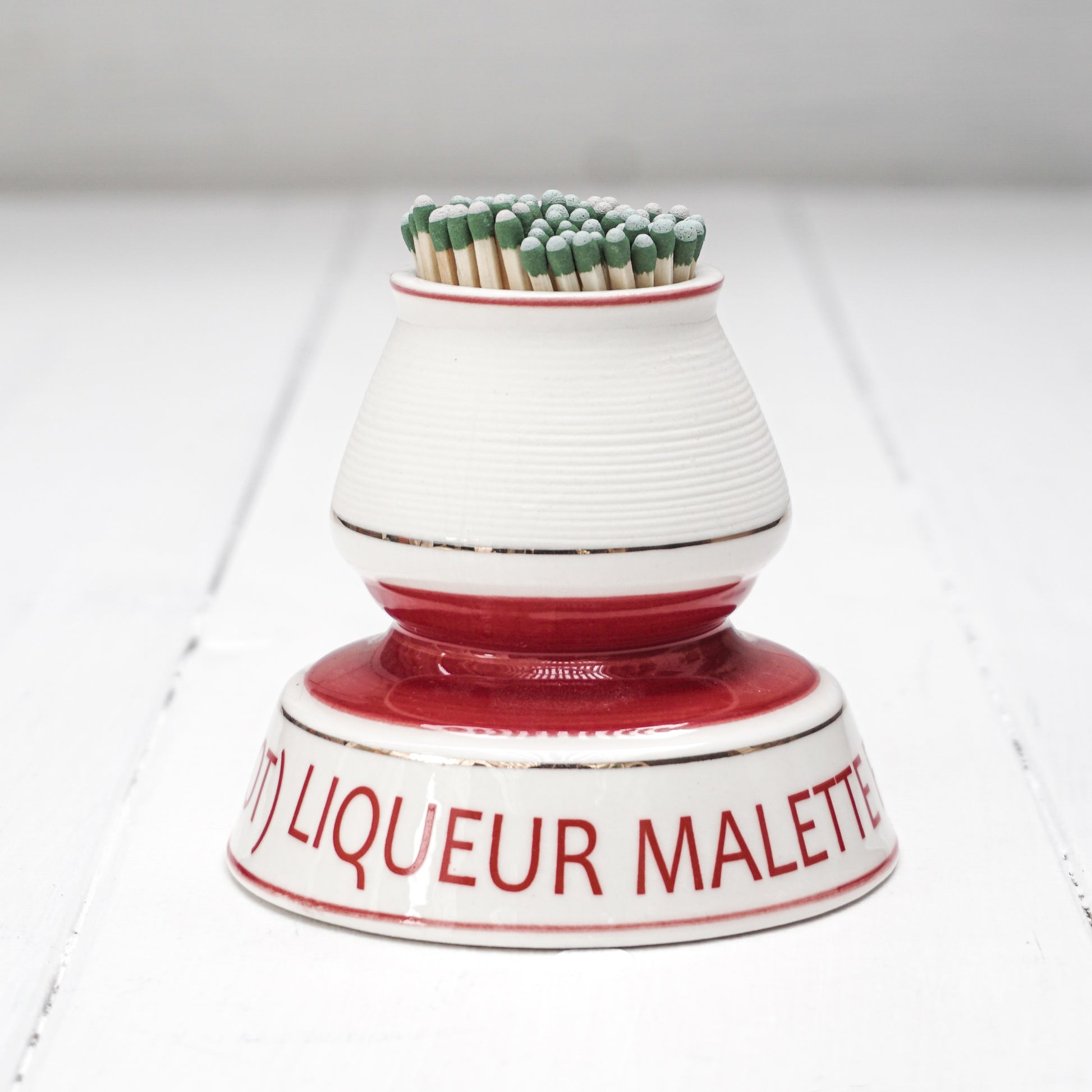 white and red ceramic match strike holder with red French lettering