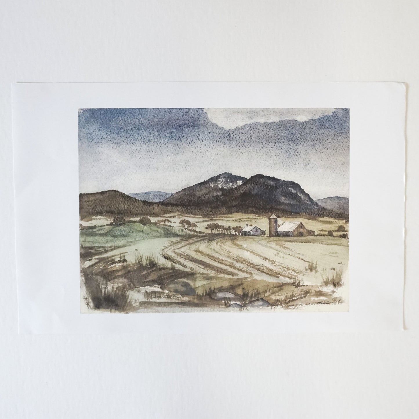 watercolor of farmscape with silo, barn and mountains