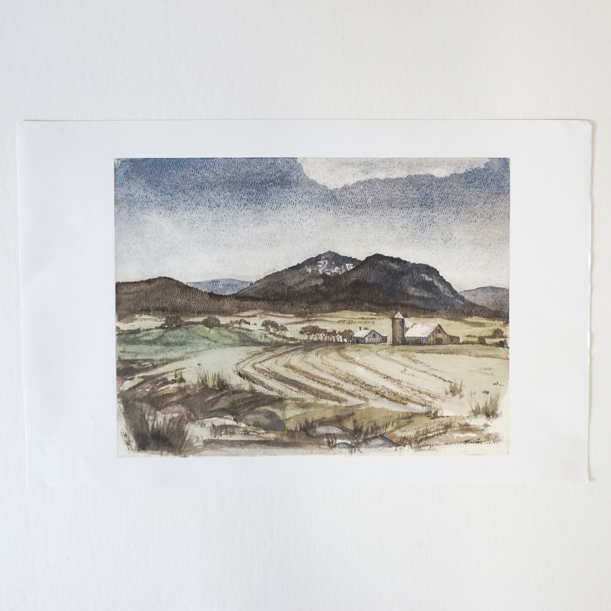watercolor of farmscape with silo, barn and mountains