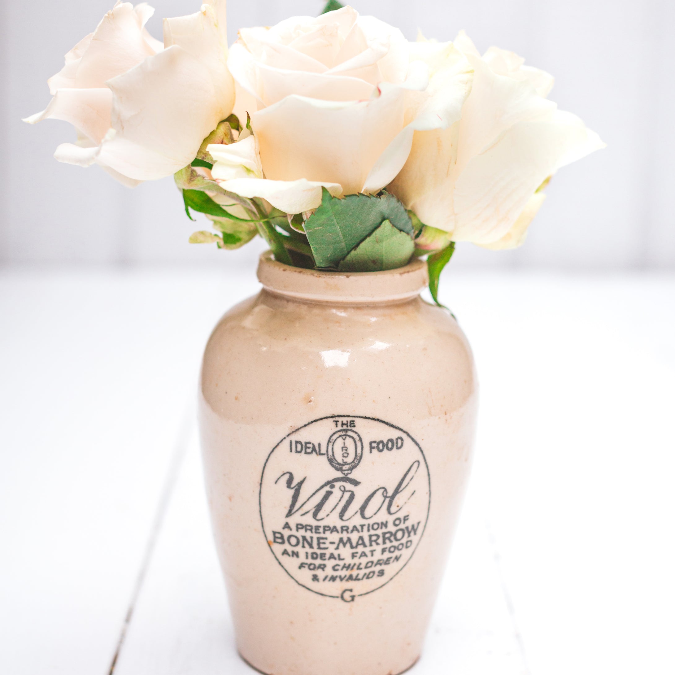 cream colored ceramic vase with black logo