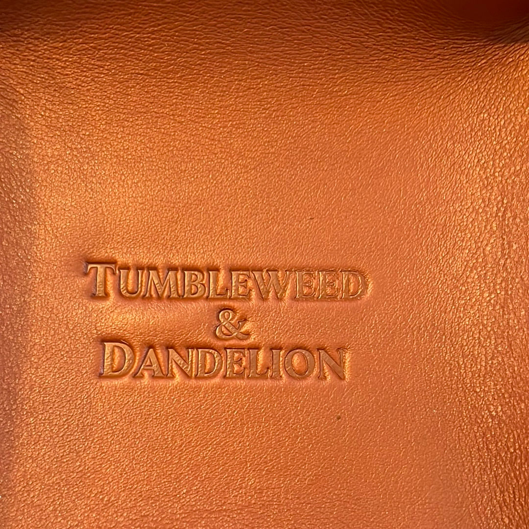 brown leather catch all tray with "tumbleweed and dandelion" embossed in the middle